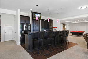 Entertainment space featuring a dark wood-finish bar with seating for six, dark cabinetry, and integrated appliances