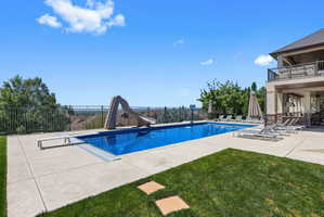 Outdoor swimming pool featuring a diving board and waterslide