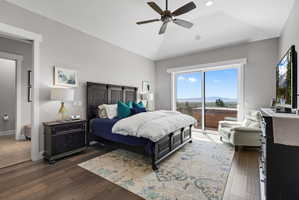 Vaulted ceiling bedroom with a ceiling fan, wood-finish flooring, and sliding glass doors opening to a balcony