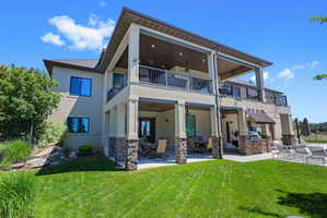 Multi-level exterior featuring covered patios, covered balconies with wrought iron railings, and stone-clad columns