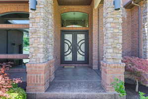Stately brick and stone exterior featuring a double entry door with decorative glass inserts and an arched transom window
