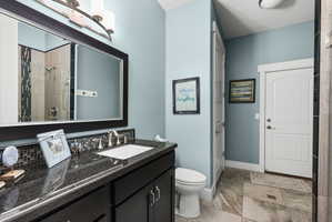 Vanity featuring a dark countertop, undermount sink, and mosaic tile backsplash