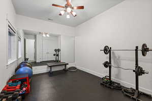 Dedicated exercise room featuring dark rubber flooring, expansive wall-mounted mirrors, and an angled ceiling
