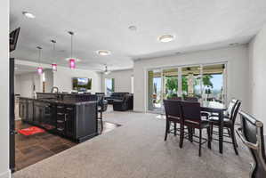 Spacious open-concept recreation room featuring a large kitchen island with dark cabinetry and a stone-finish countertop, a built-in sink with a gooseneck faucet, and recessed lighting