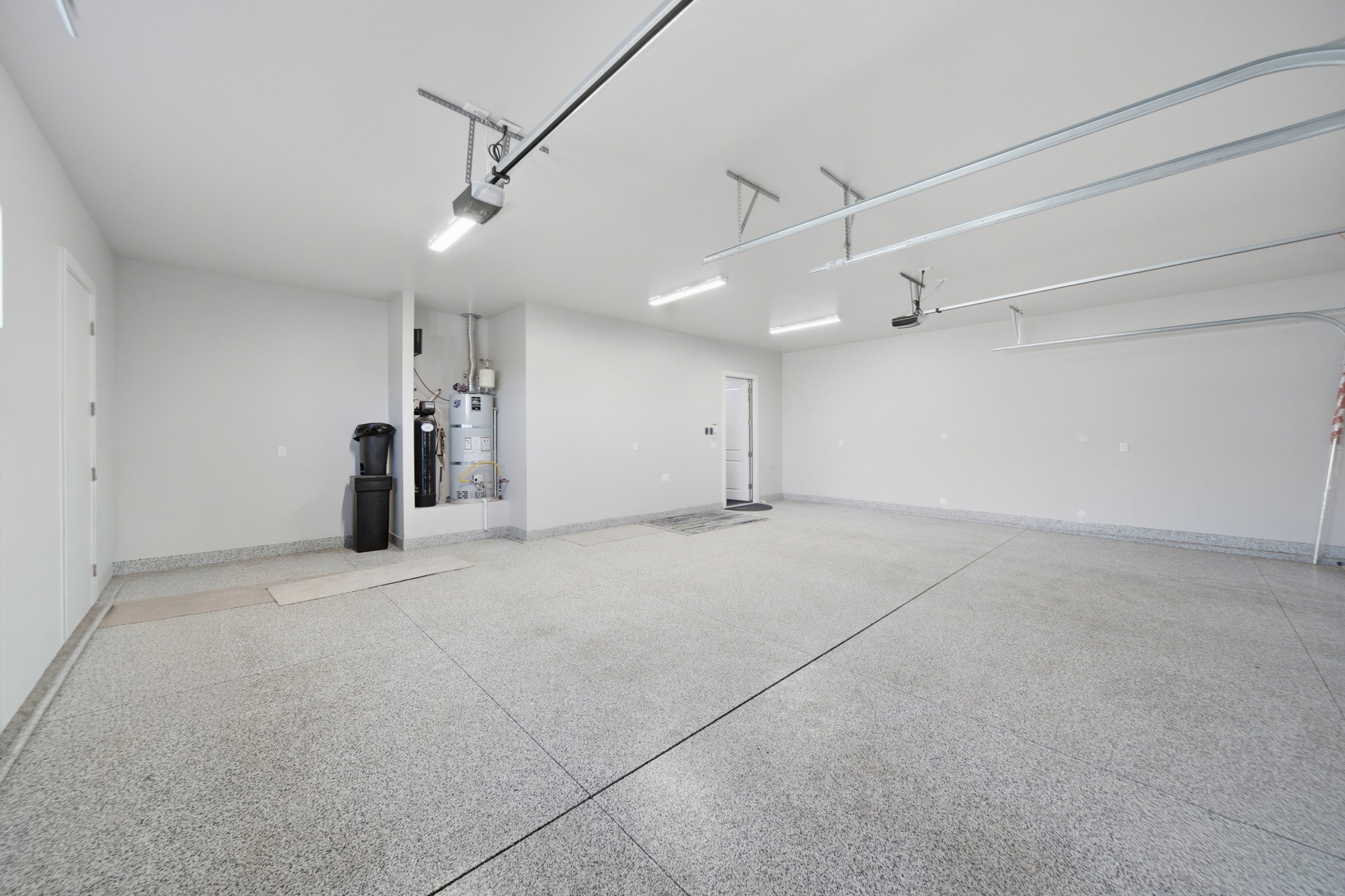 Spacious garage with epoxy flooring, white walls, and overhead track lighting