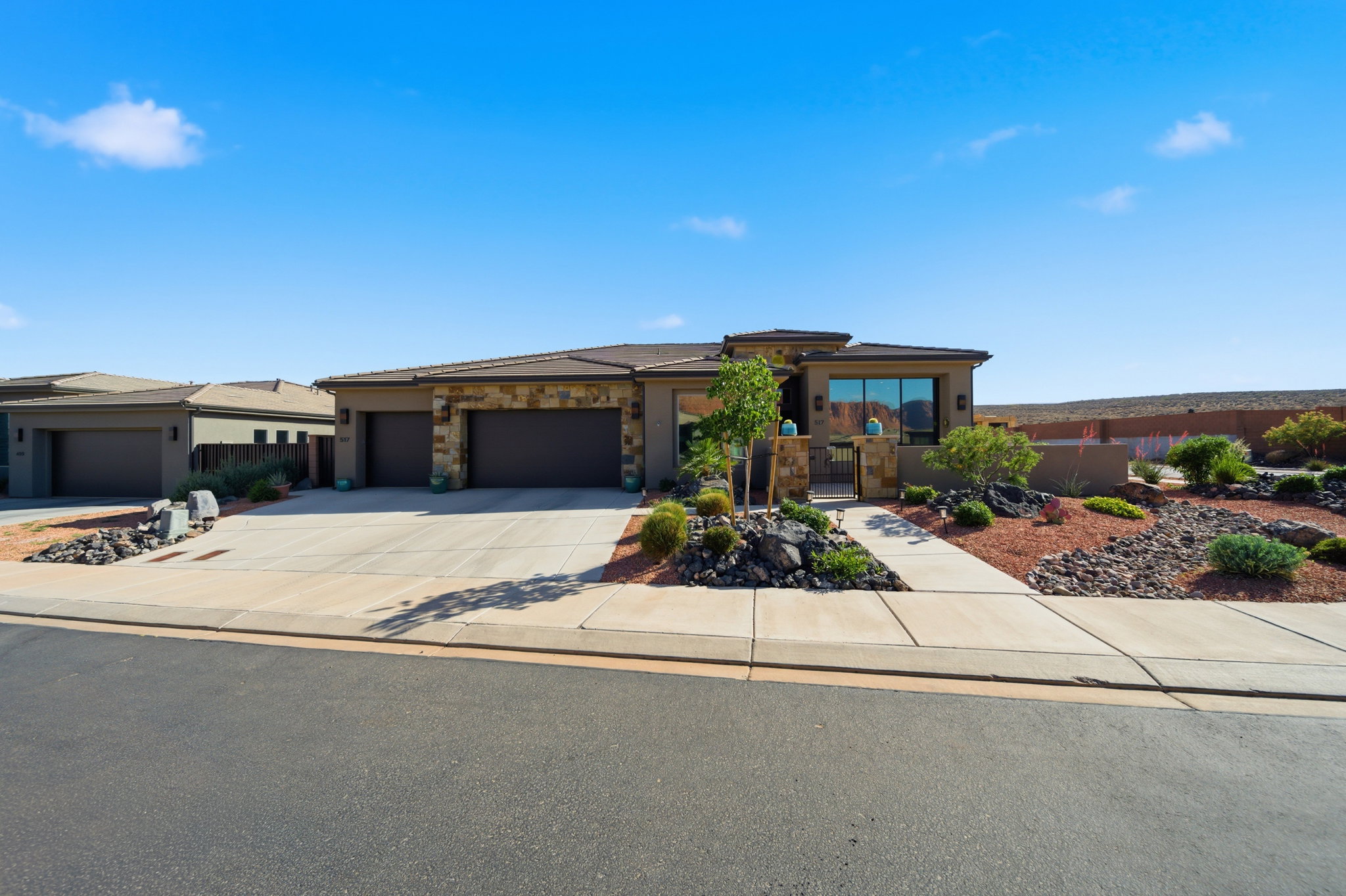 Modern desert-style residence with a two-car garage, stone façade accents, and a concrete driveway