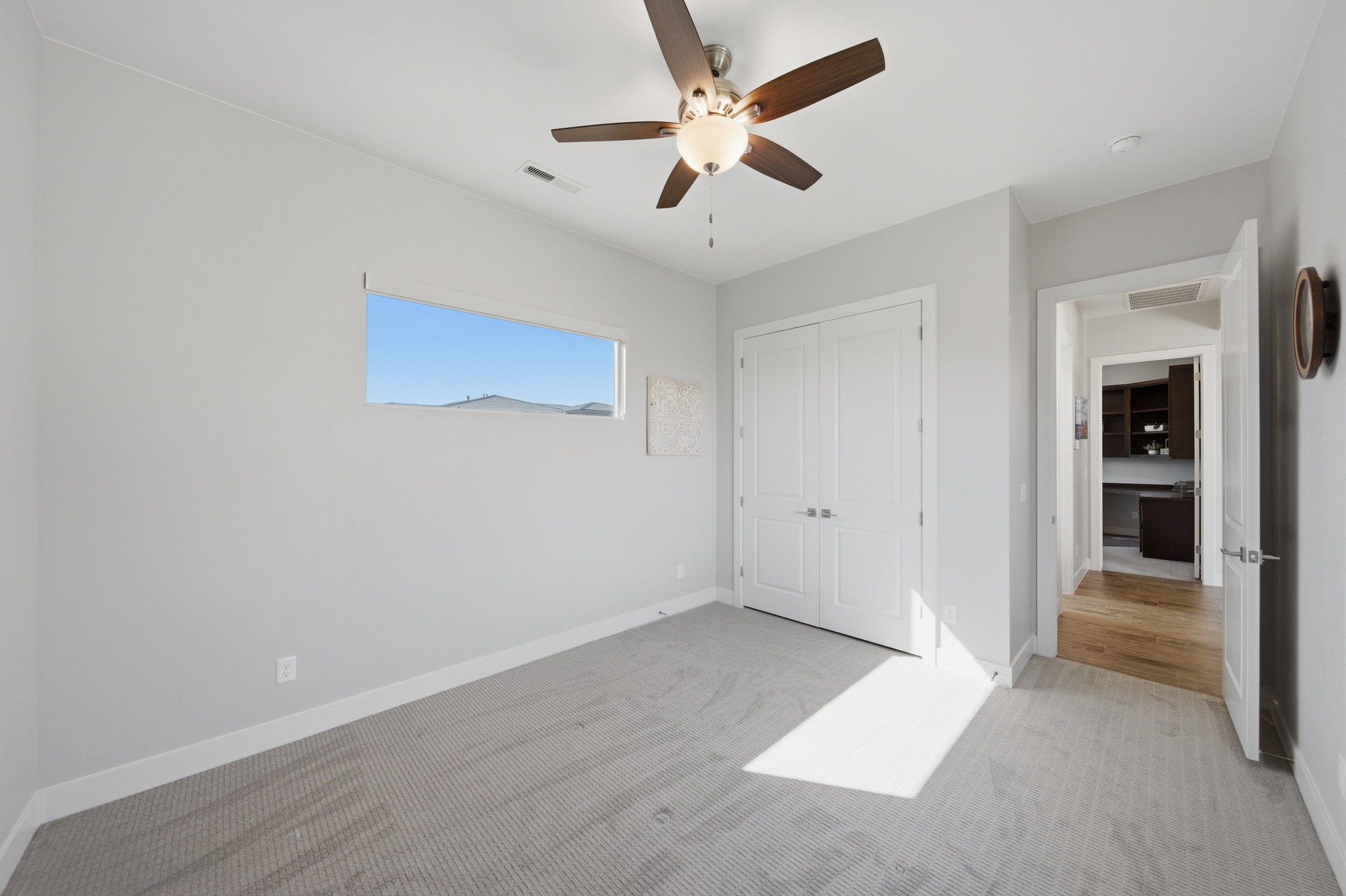 Interior room featuring light gray walls, a horizontal window with distant mountain scenery, and a ceiling fan with light fixture