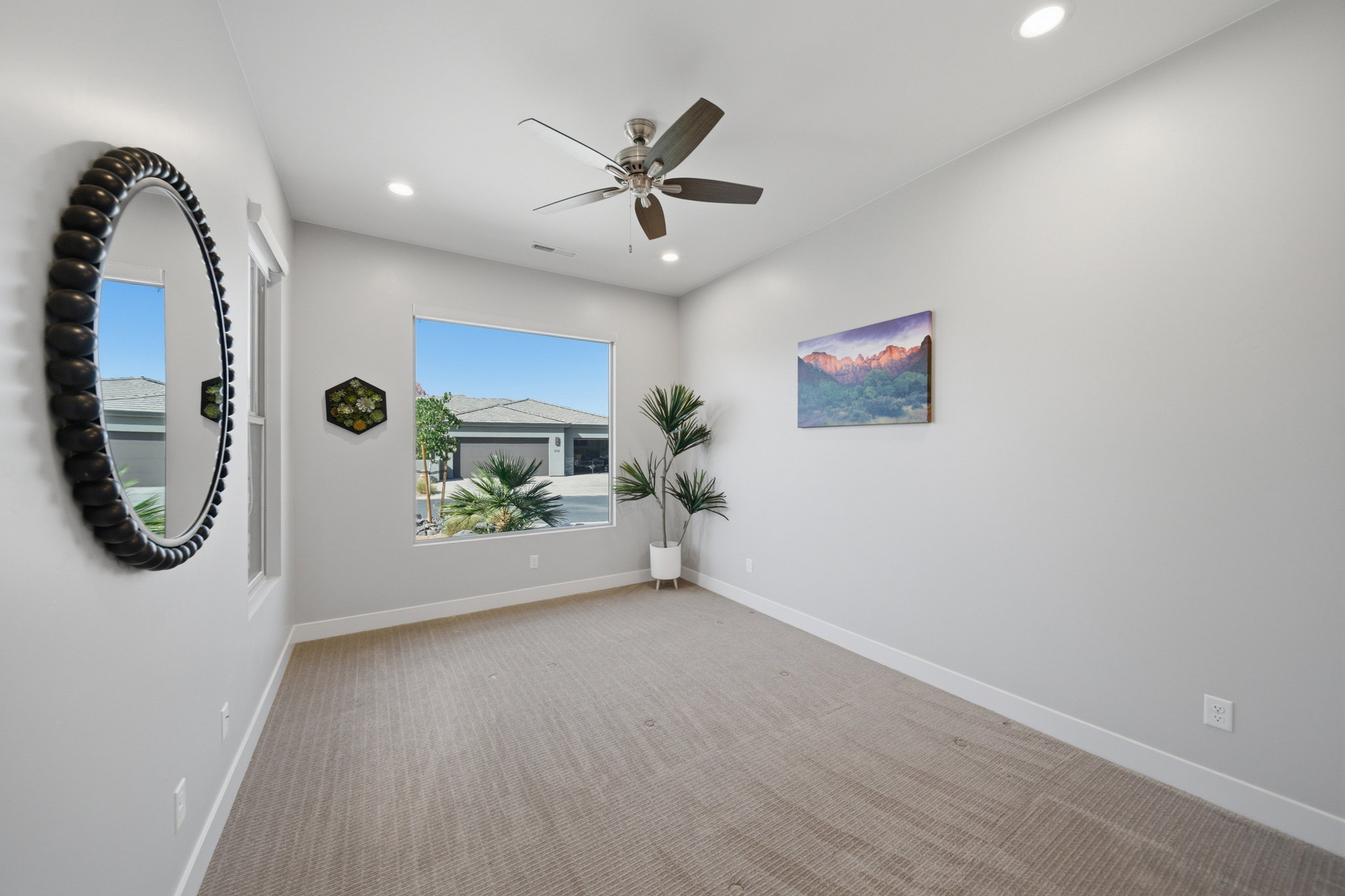 Spacious room featuring neutral carpet flooring, recessed lighting, and a modern ceiling fan