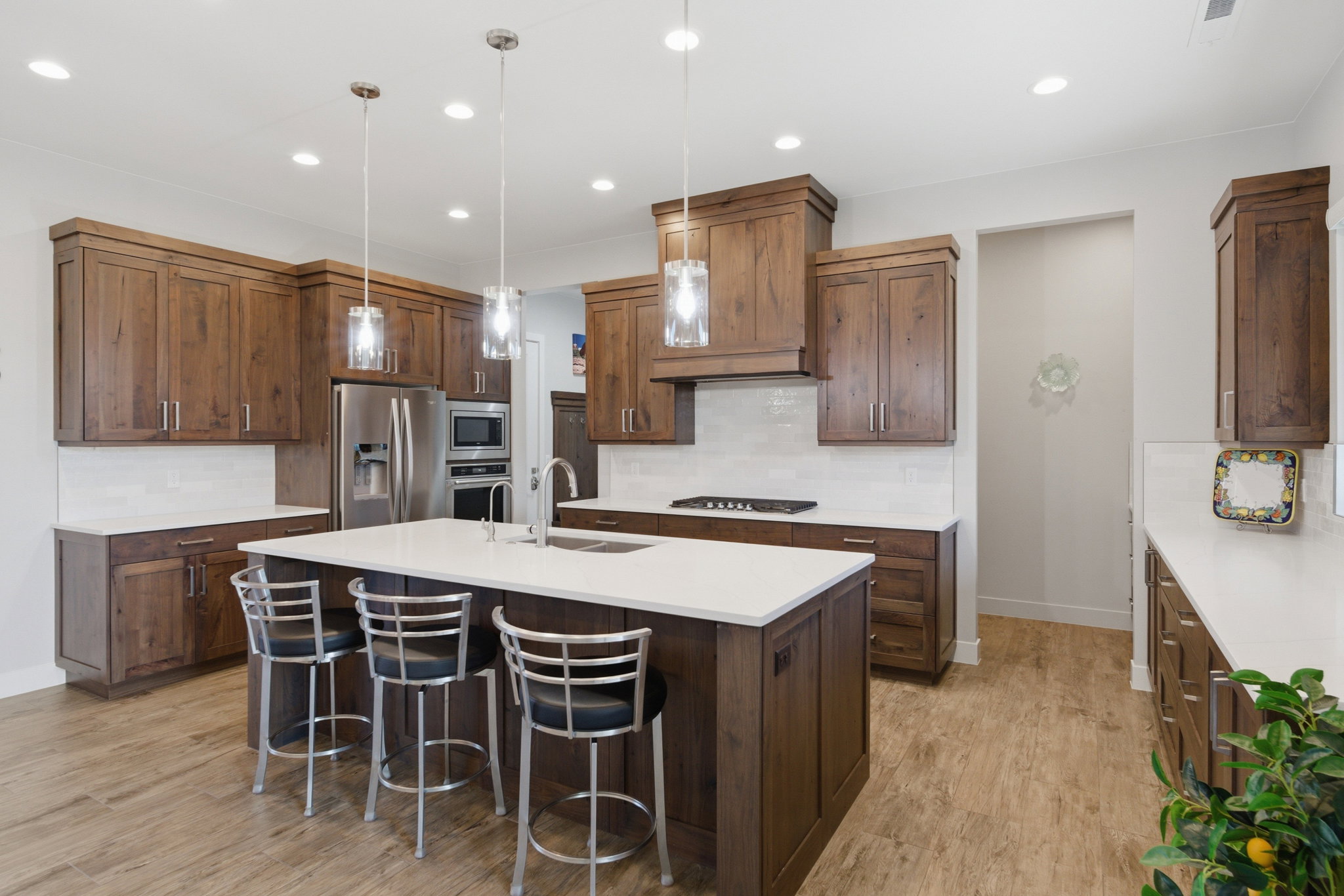 Kitchen featuring wood-finish cabinetry, white countertops, a central island with pendant lighting, stainless steel appliances, and wood-finish flooring