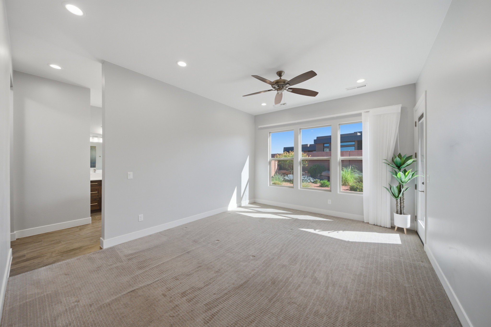 Spacious room featuring light-colored carpeting, recessed lighting, and a ceiling fan