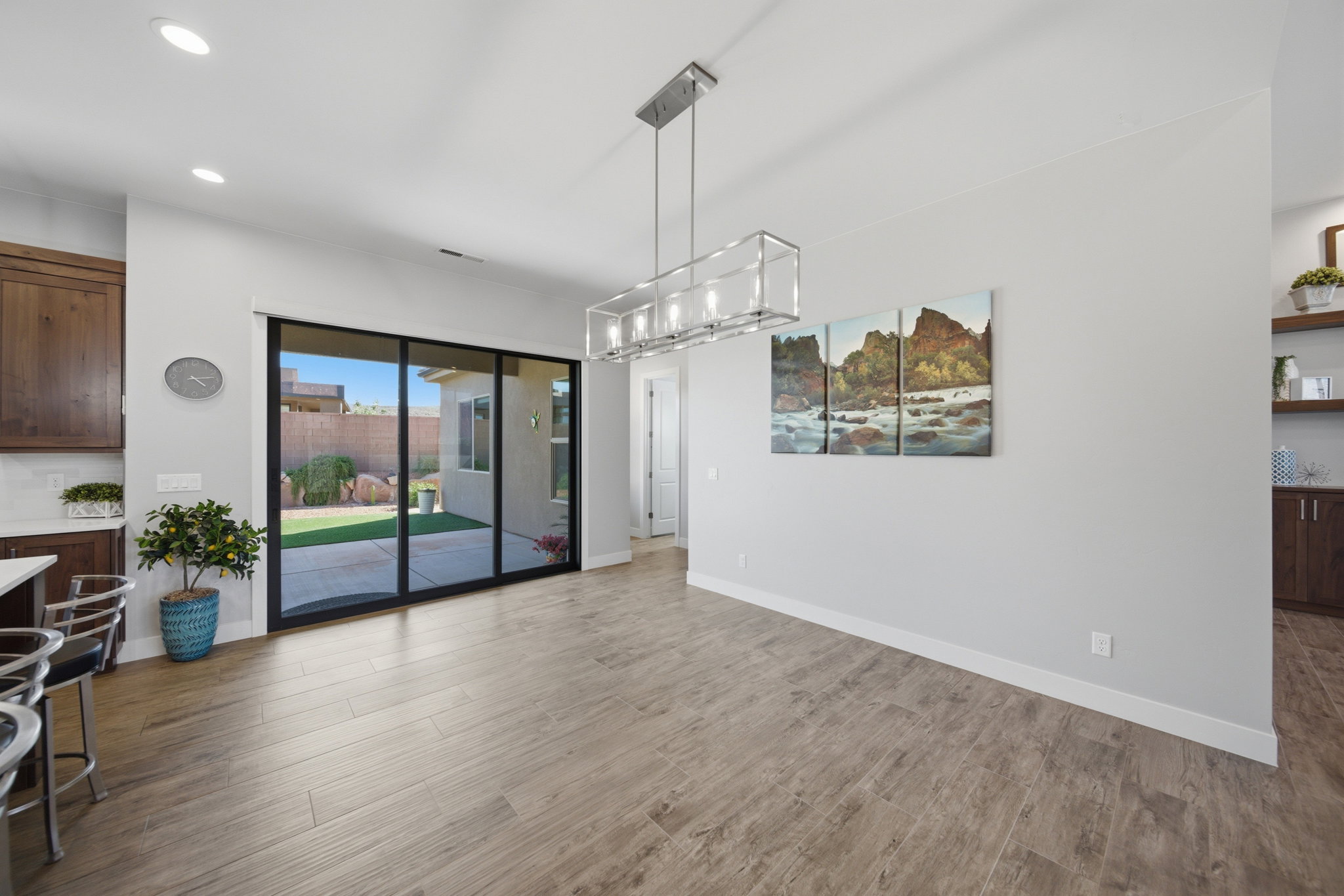 Spacious dining area featuring wood-finish flooring, a contemporary linear chandelier, and recessed lighting