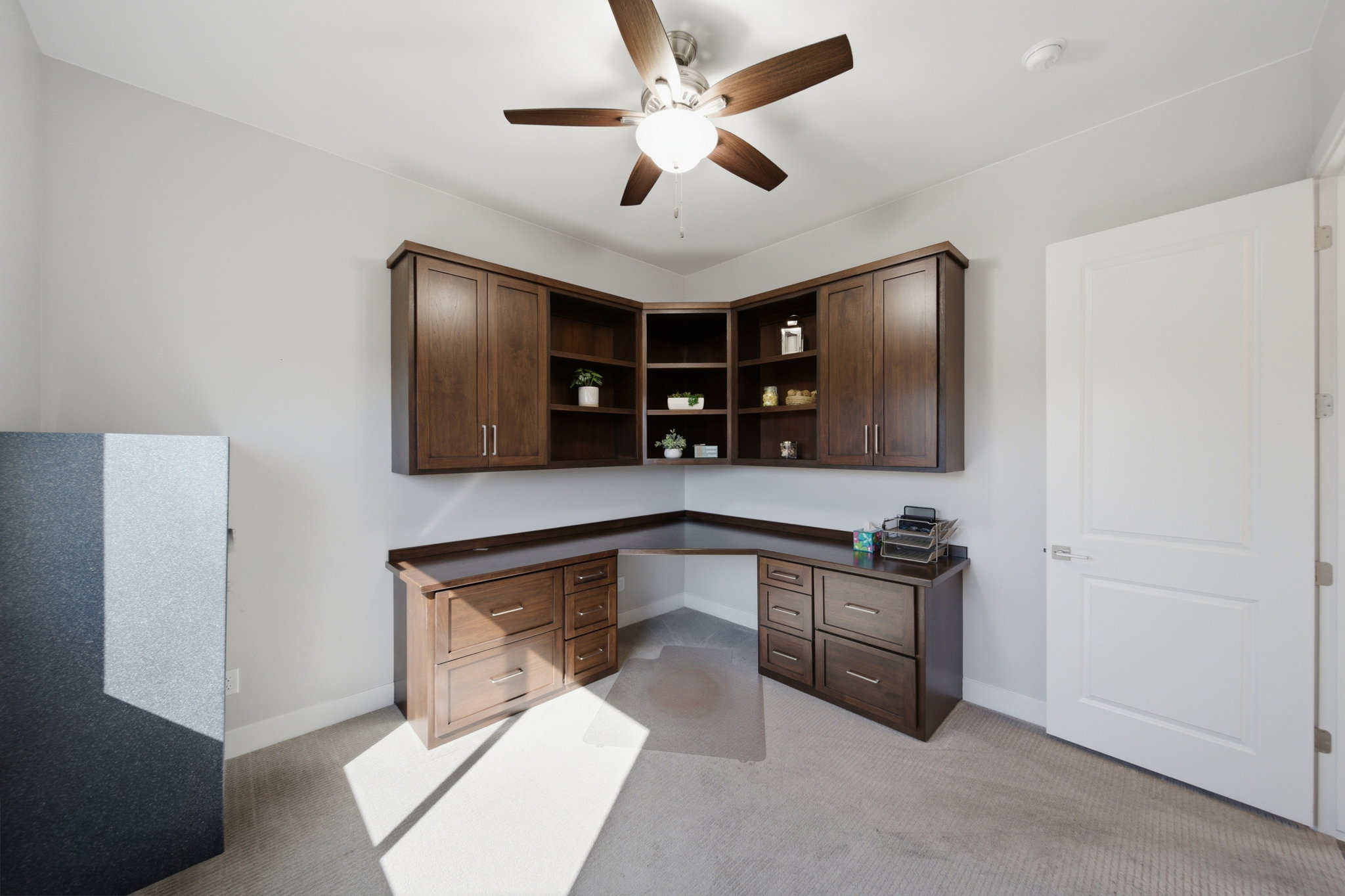 Built-in L-shaped desk with rich wood-finish cabinetry and overhead shelving