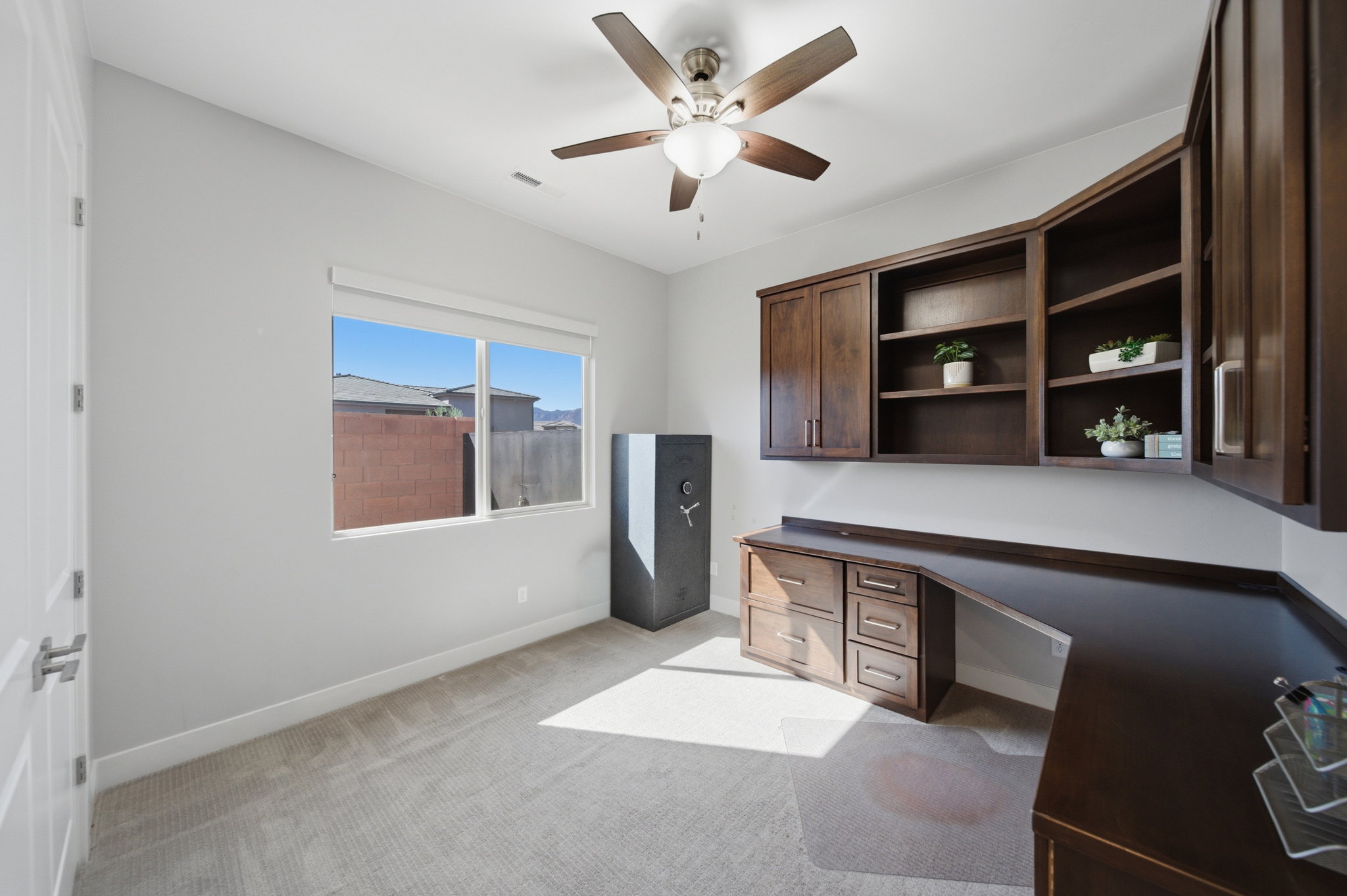 Room featuring built-in wood-finish cabinetry, a coordinated desk, and a ceiling fan with integrated lighting