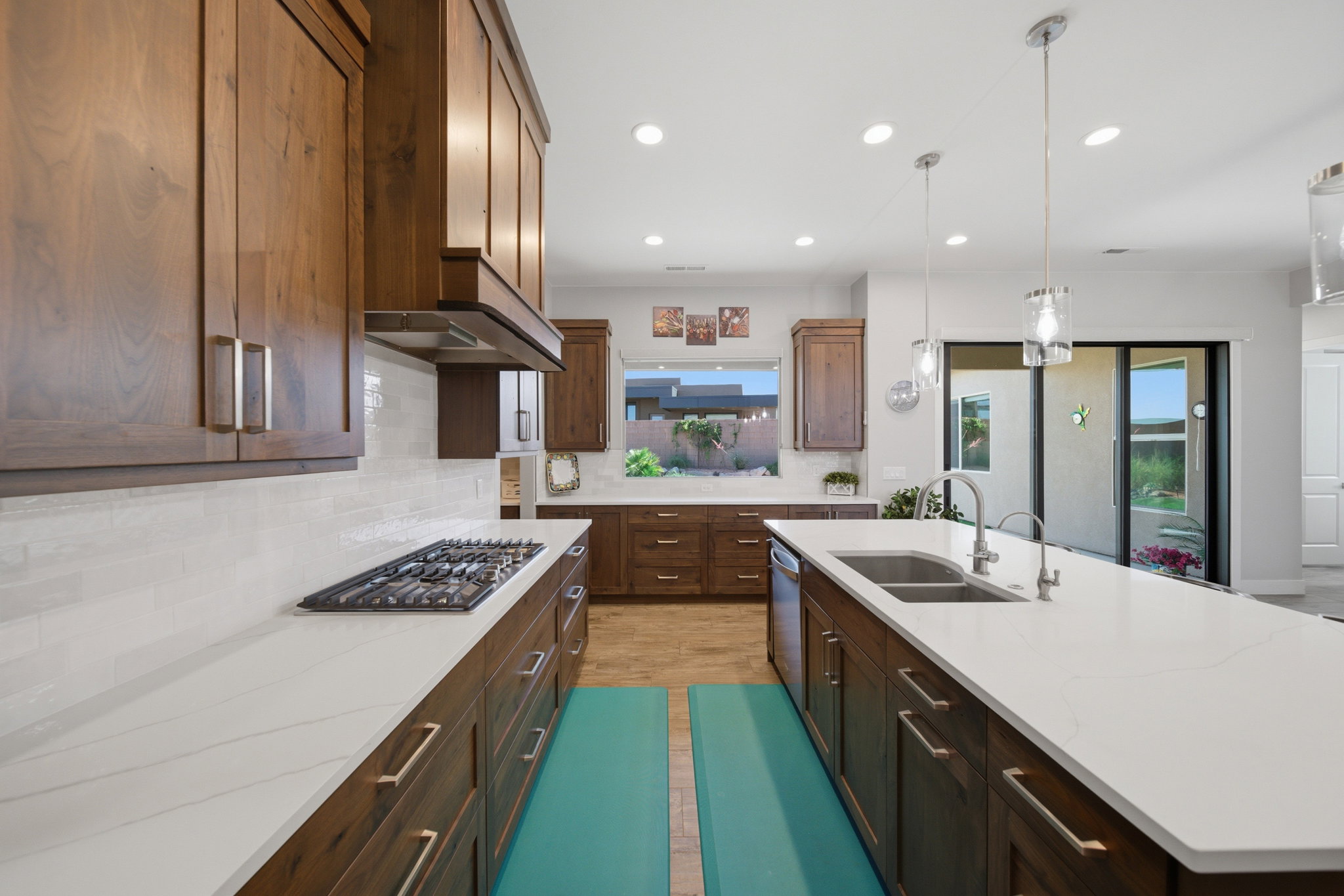 Expansive kitchen with rich wood cabinetry, light-toned countertops, and a gas cooktop