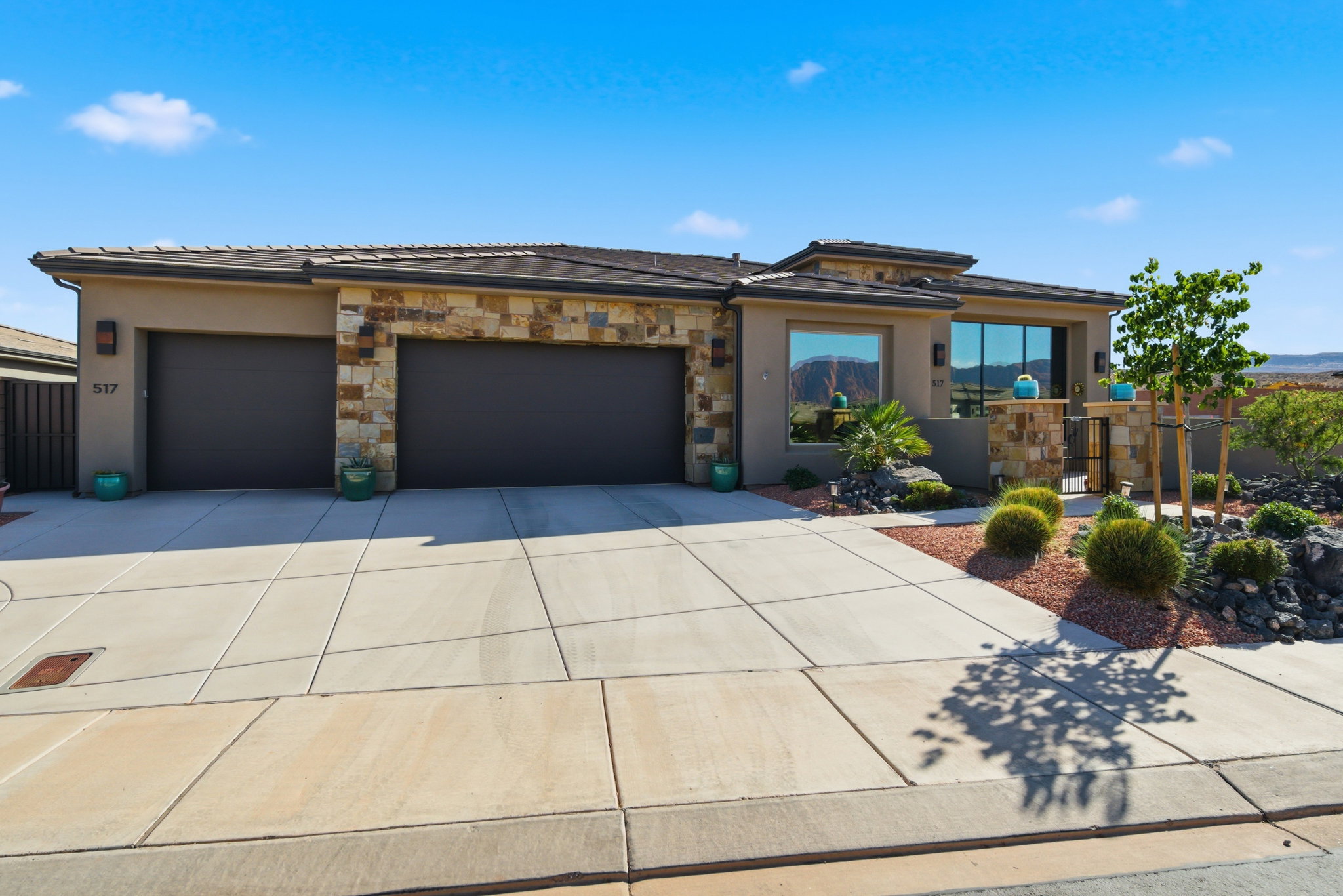 Contemporary stucco exterior featuring stone accents, a multi-car driveway, and integrated two-car garage