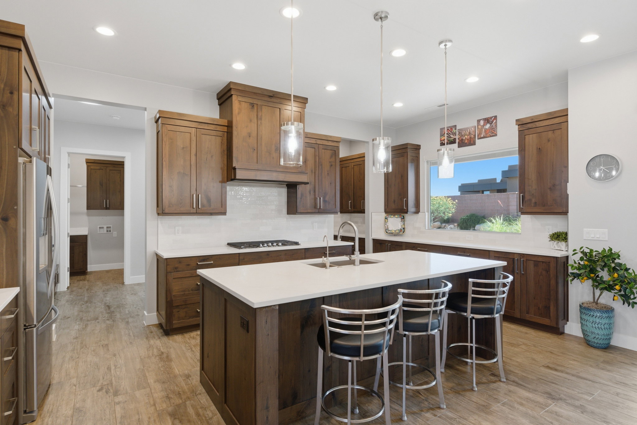 Spacious kitchen featuring an expansive center island with seating, wood-finish cabinetry, light-toned countertops, a tile backsplash, and wood-finish flooring