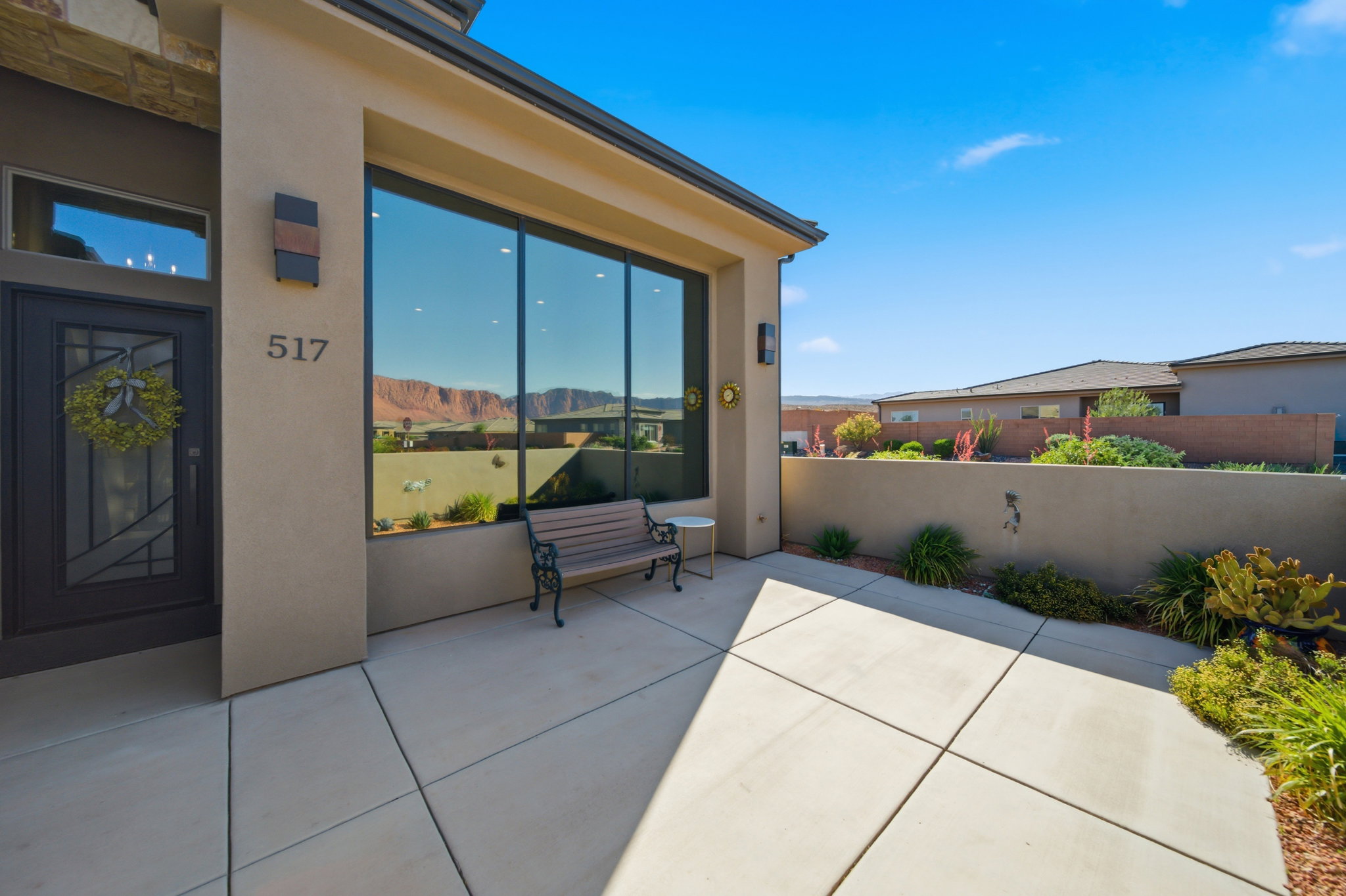 Contemporary stucco exterior with a large picture window, a dark-paneled entry door, and concrete patio