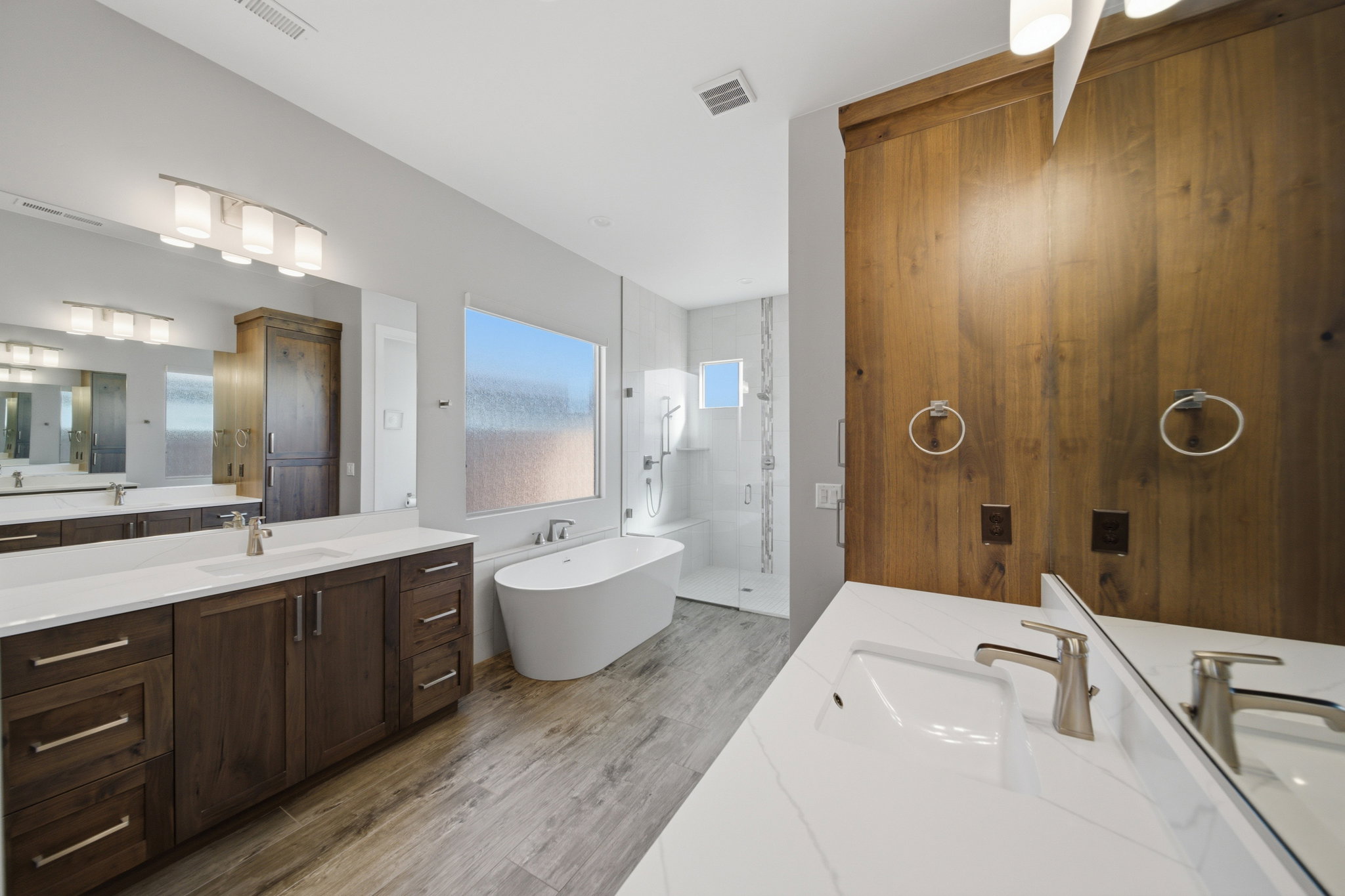 Bathroom featuring wood-finish flooring, a freestanding bathtub, and a glass-enclosed shower