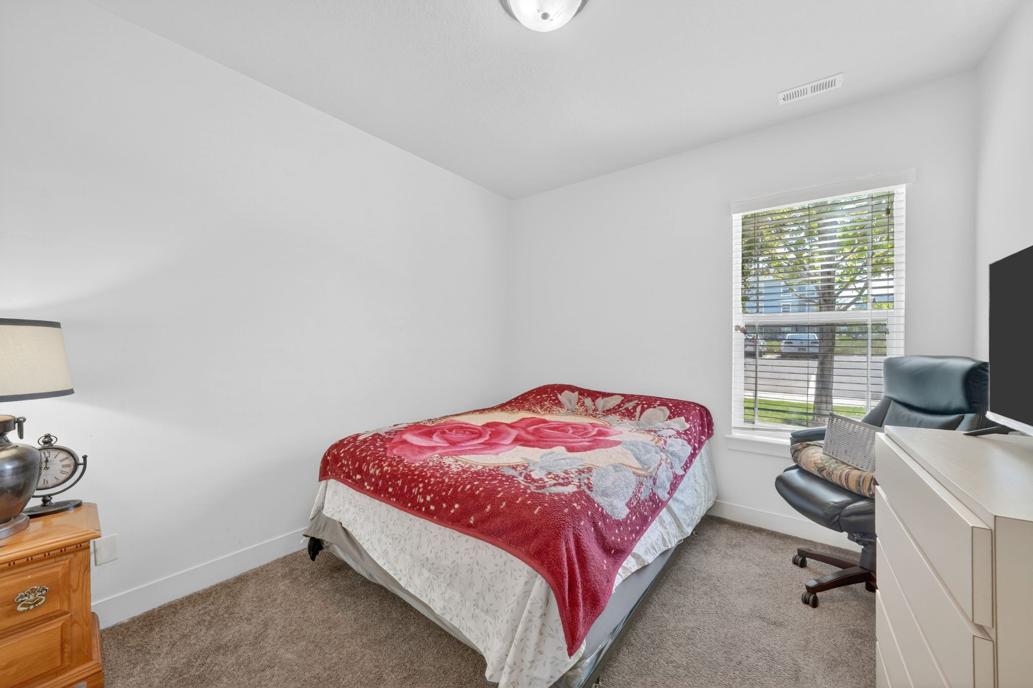 Carpeted room with white walls, a single window featuring blinds, and a ceiling light fixture