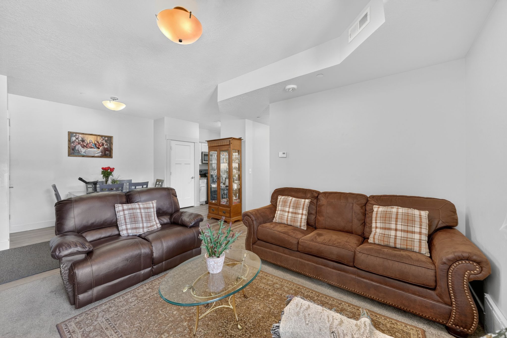 Open-concept living area featuring light-toned walls and ceiling, recessed lighting, and a blend of carpeted and wood-finish flooring