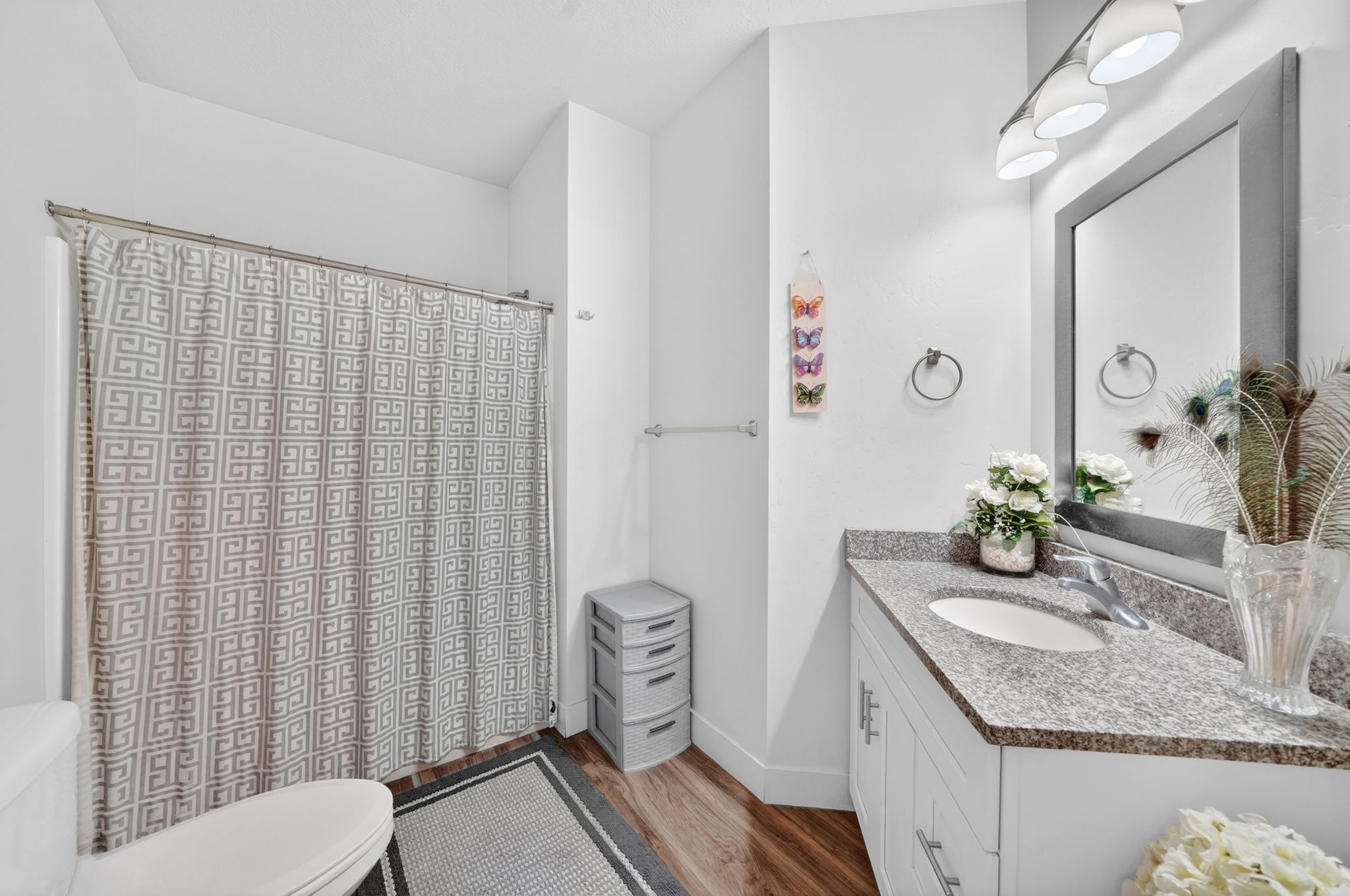 Bathroom featuring a single vanity with granite countertop, undermount sink, and chrome faucet
