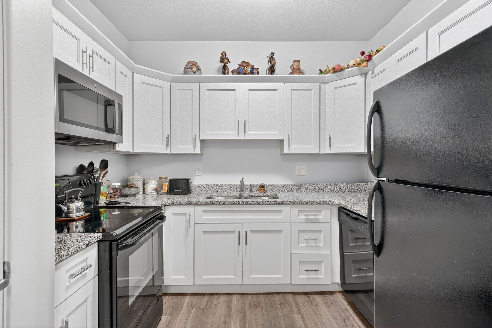 Kitchen featuring white shaker-style cabinetry, light-toned countertops, and wood-finish flooring