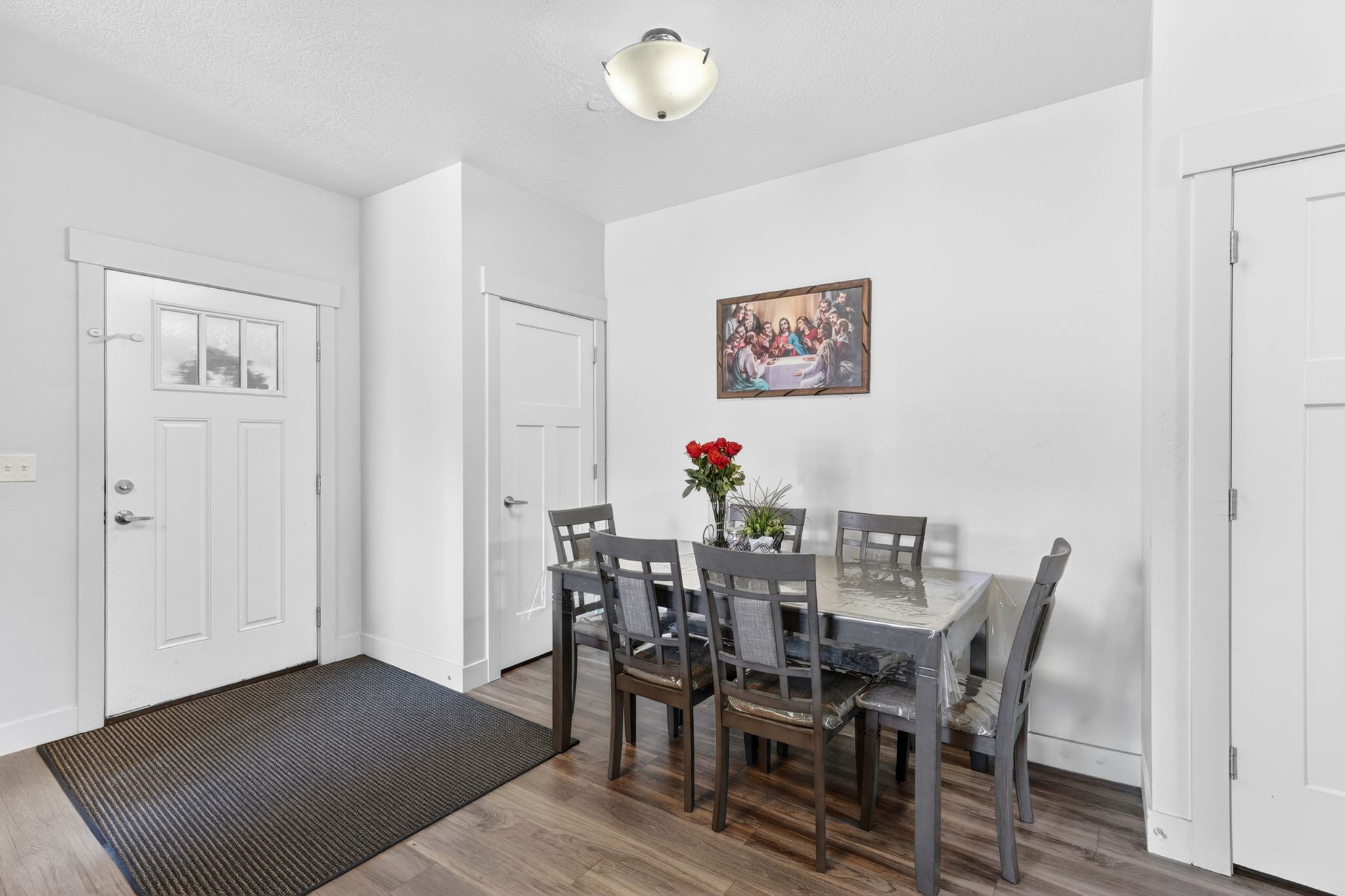 Entryway and dining space featuring wood-finish flooring, white trim, a decorative front door with transom lites, and a modern ceiling light fixture