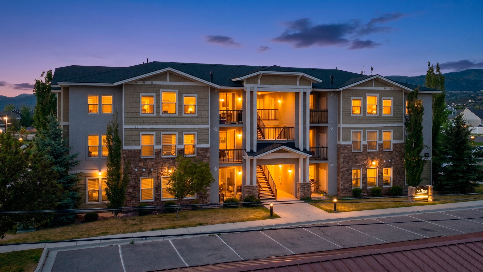 Three-story multi-unit building featuring a stone and siding exterior