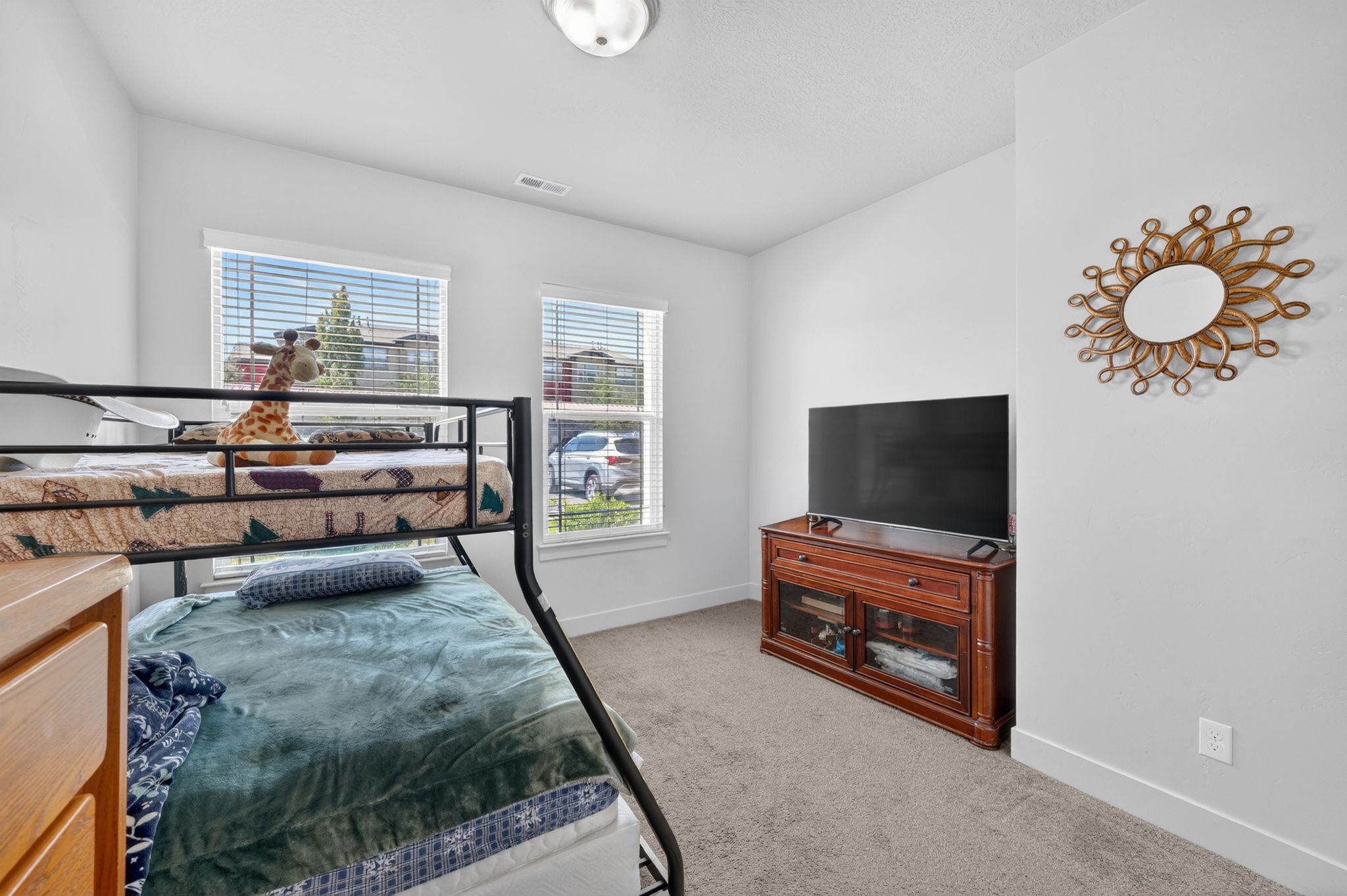 Bright room featuring two windows with blinds, light gray carpet flooring, and white baseboards