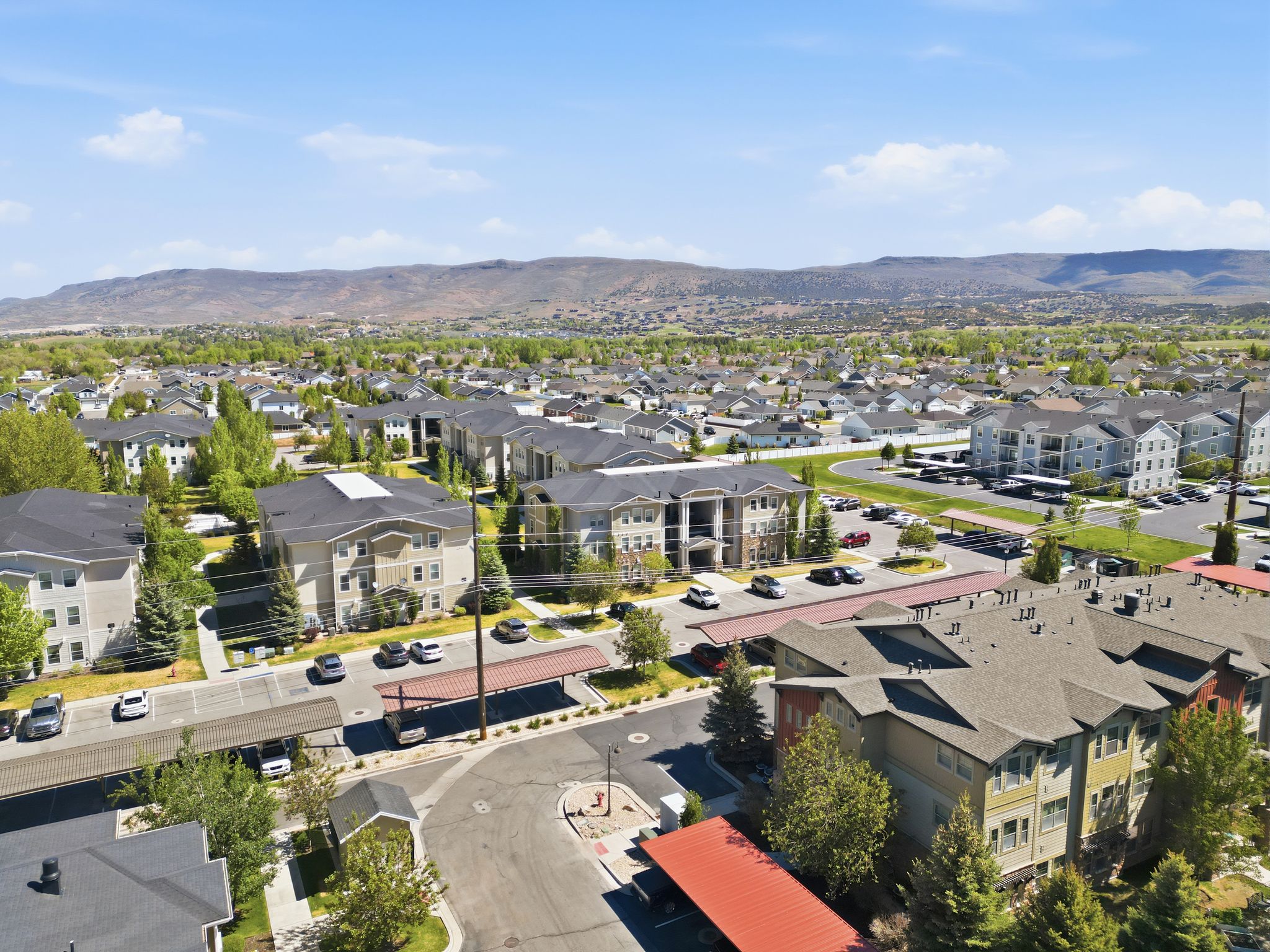 Aerial perspective showcasing a community of multi-story residential buildings with surrounding paved parking areas