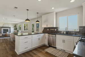 Open-concept kitchen with white cabinetry, dark countertops, and a subway tile backsplash