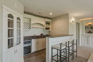 Wet bar featuring white cabinetry, a built-in wine rack, and a dark countertop with an integrated sink