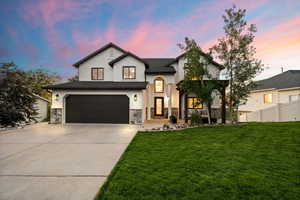 Stucco and stone exterior featuring a black garage door and dark-framed windows