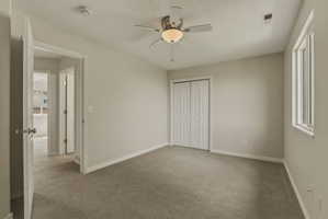 Carpeted bedroom featuring a double-door closet, a ceiling fan with integrated lighting, a window, and light-colored wall finishes