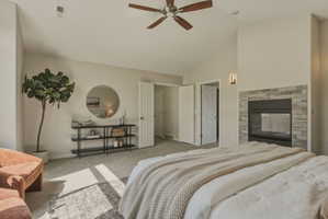 Vaulted ceiling room featuring a stone-faced fireplace with a black insert, a ceiling fan with wood-finish blades, and wall-mounted sconce lighting