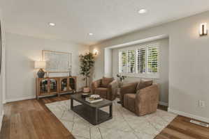 Spacious living area featuring wood-finish flooring, recessed lighting, and wall sconces