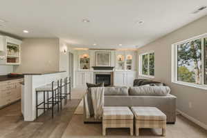 Integrated living space featuring a built-in wet bar, a fireplace with a stone surround, and custom built-in shelving