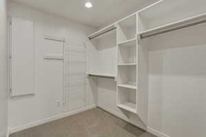 Walk-in closet featuring built-in shelving, multiple hanging rods, recessed ceiling lighting, and carpet flooring