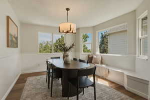 Dining area featuring wood-finish flooring, wainscoting, and multiple windows