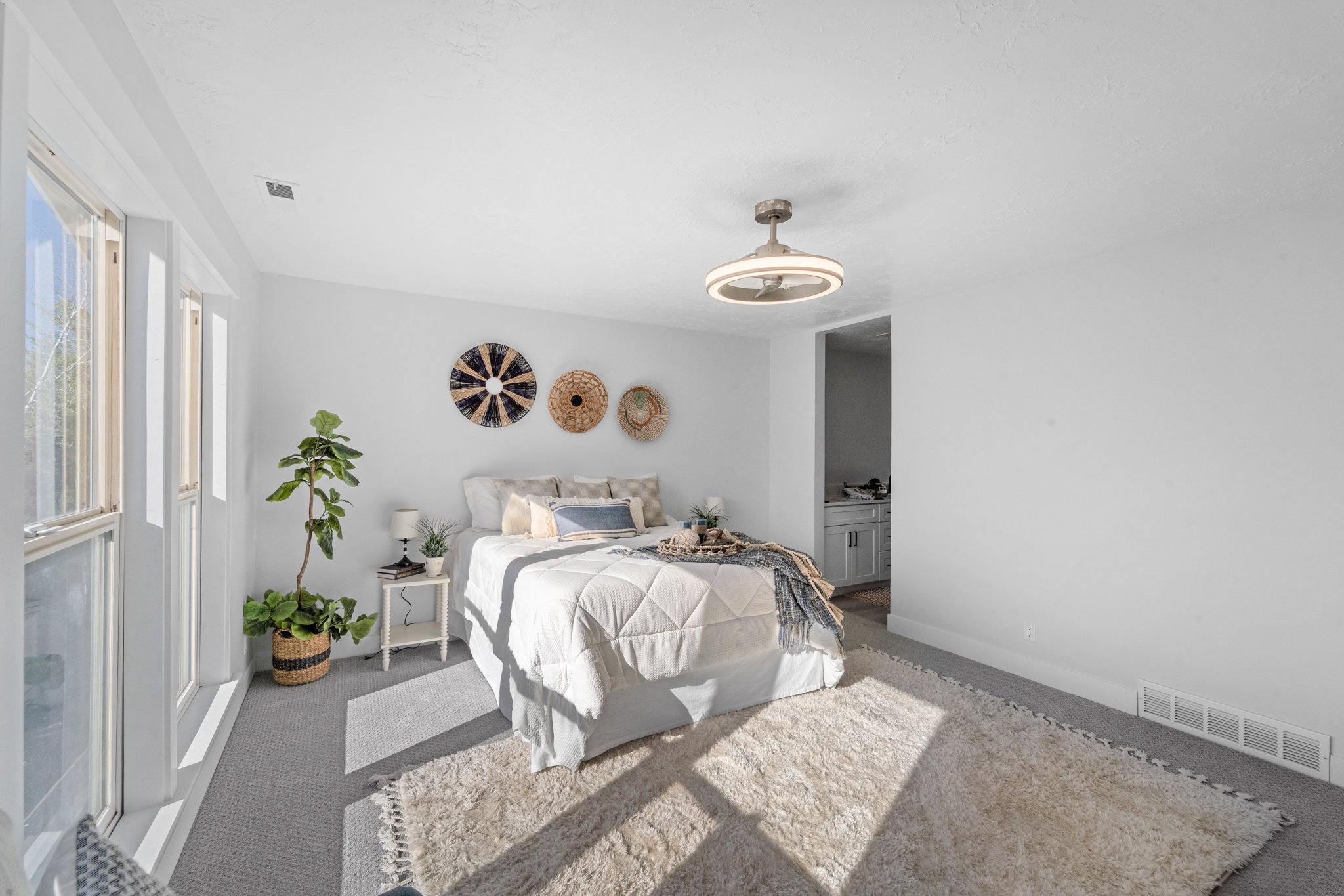 Bright interior space featuring multiple windows, a ceiling-mounted light fixture, and carpet flooring