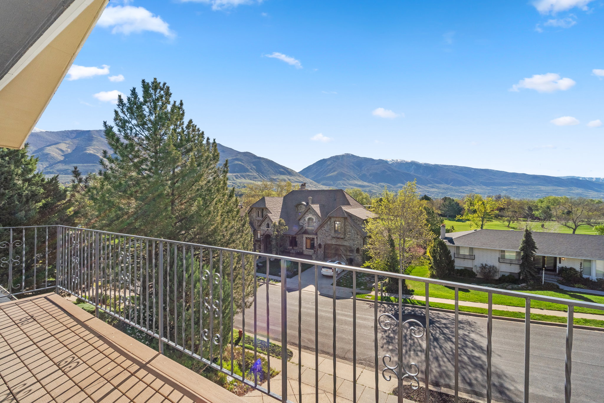 Balcony with decorative metal railing and wood-finish flooring, offering expansive mountain scenery