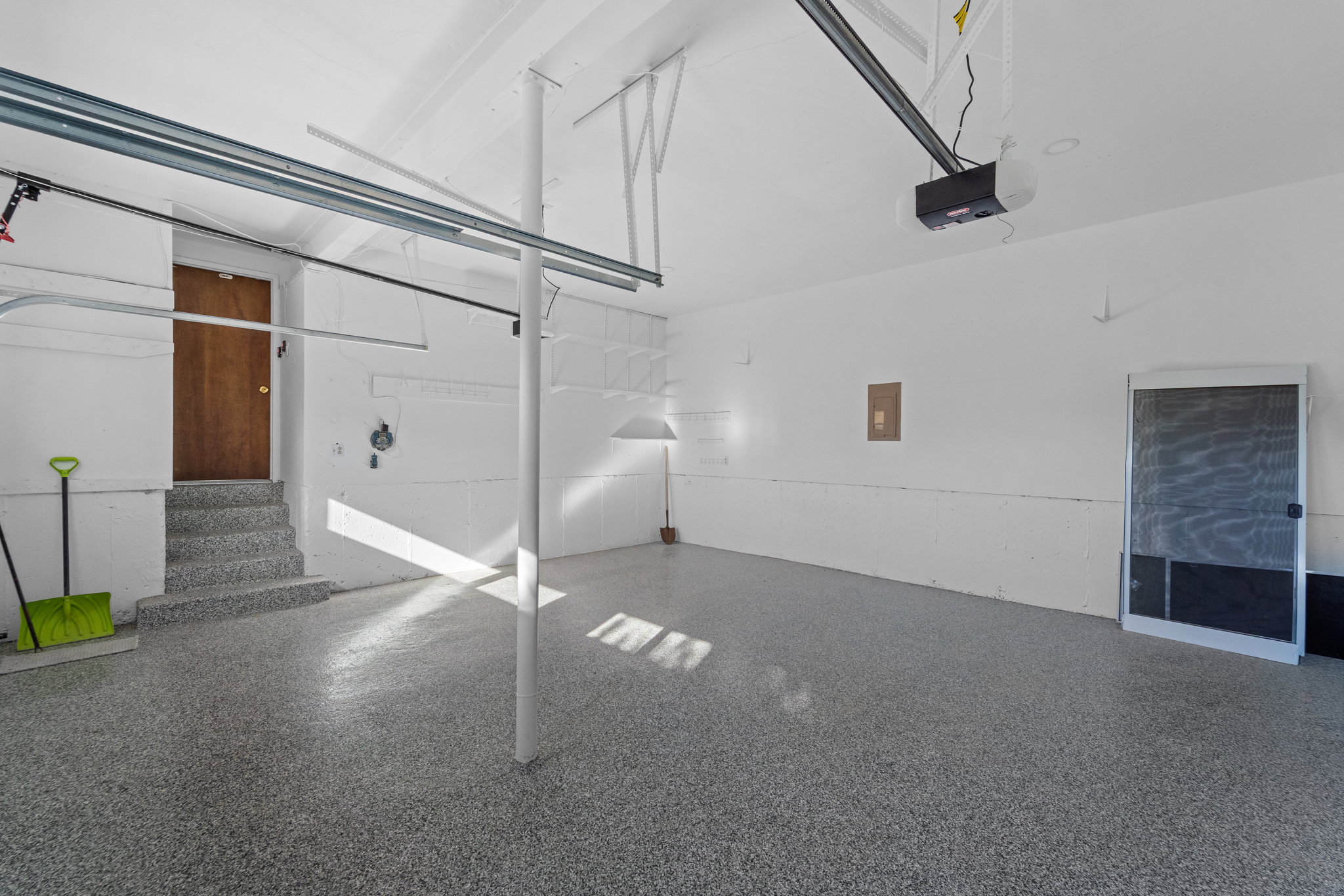 Spacious garage featuring a durable speckled epoxy floor, white painted walls, and an automatic garage door opener