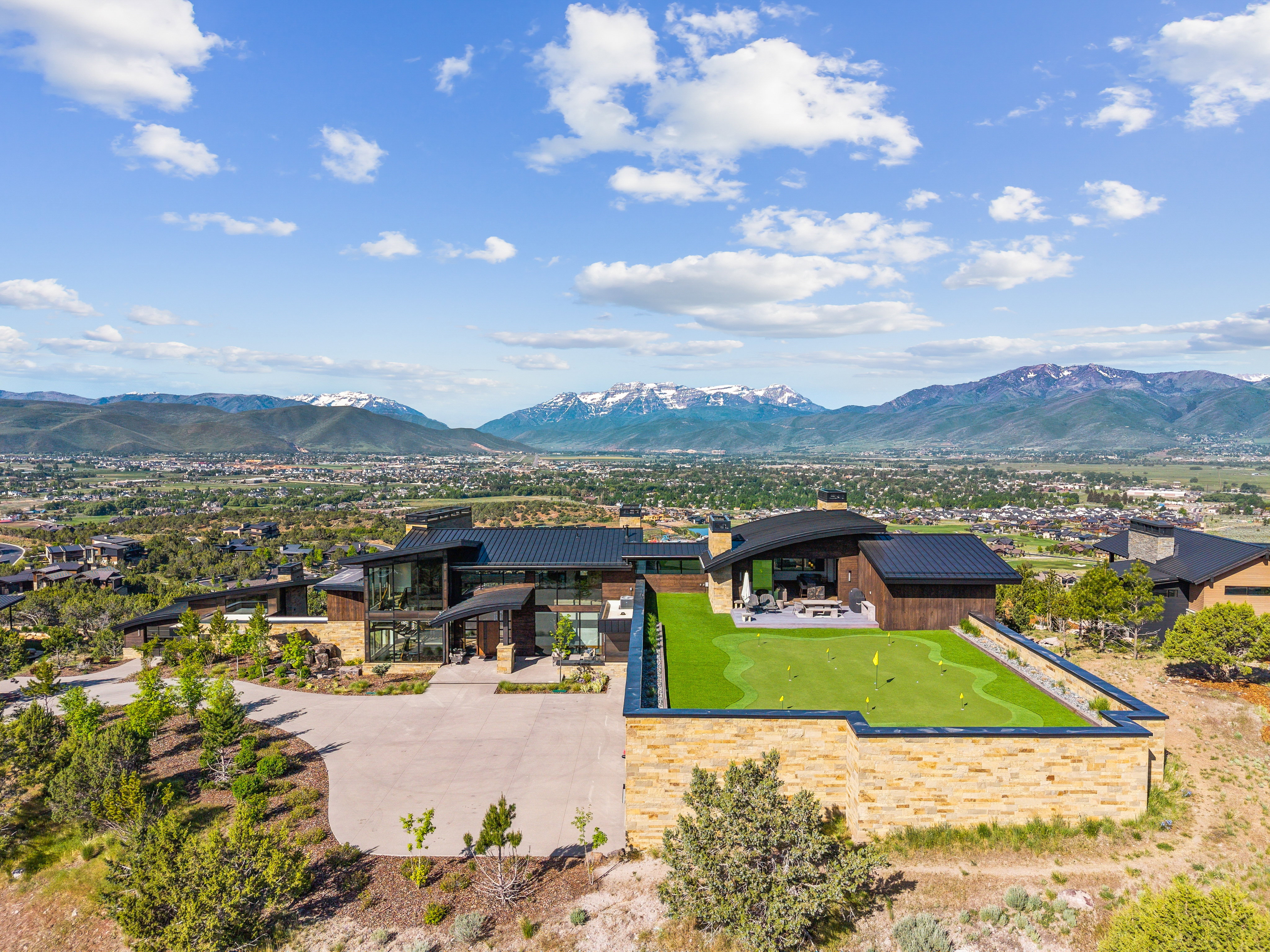 Modern architectural residence featuring a large driveway and landscaped surroundings