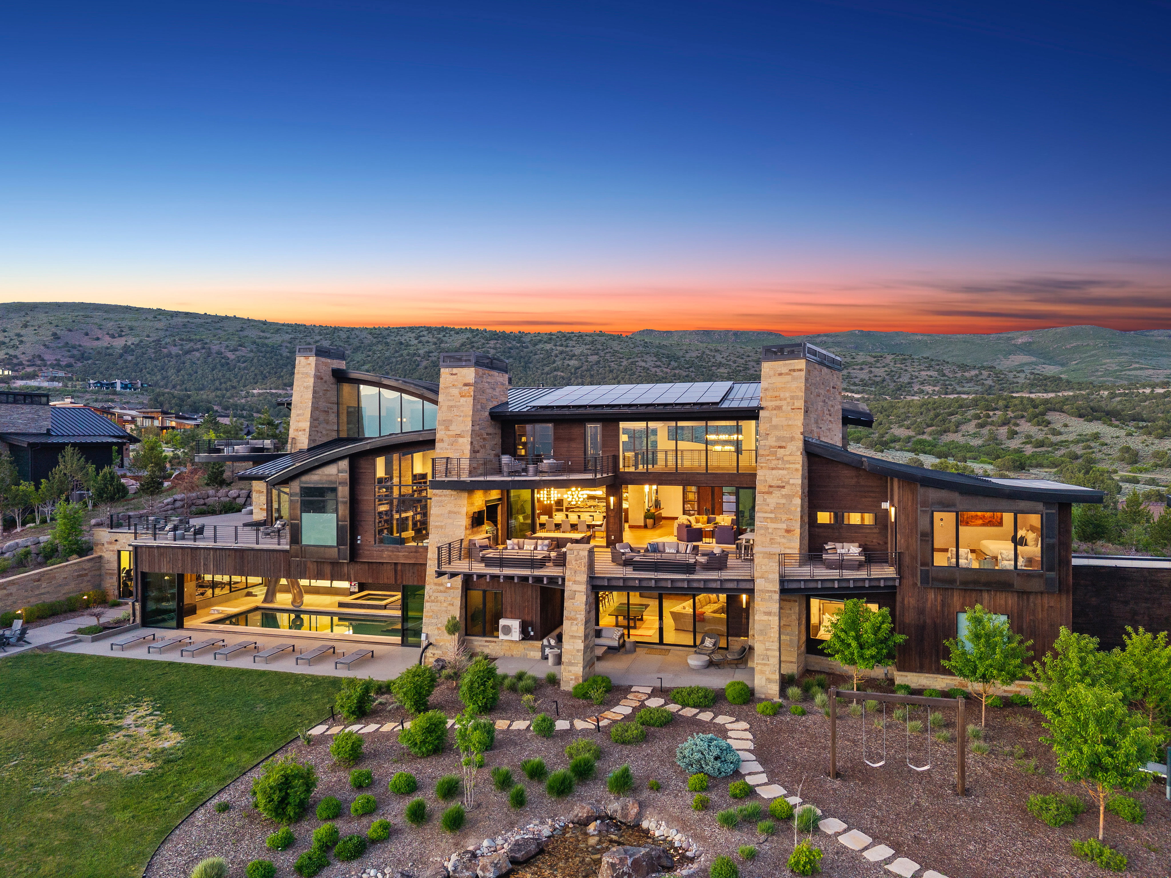 Expansive contemporary residence featuring a multi-level design, wood and stone exterior finishes, and large windows