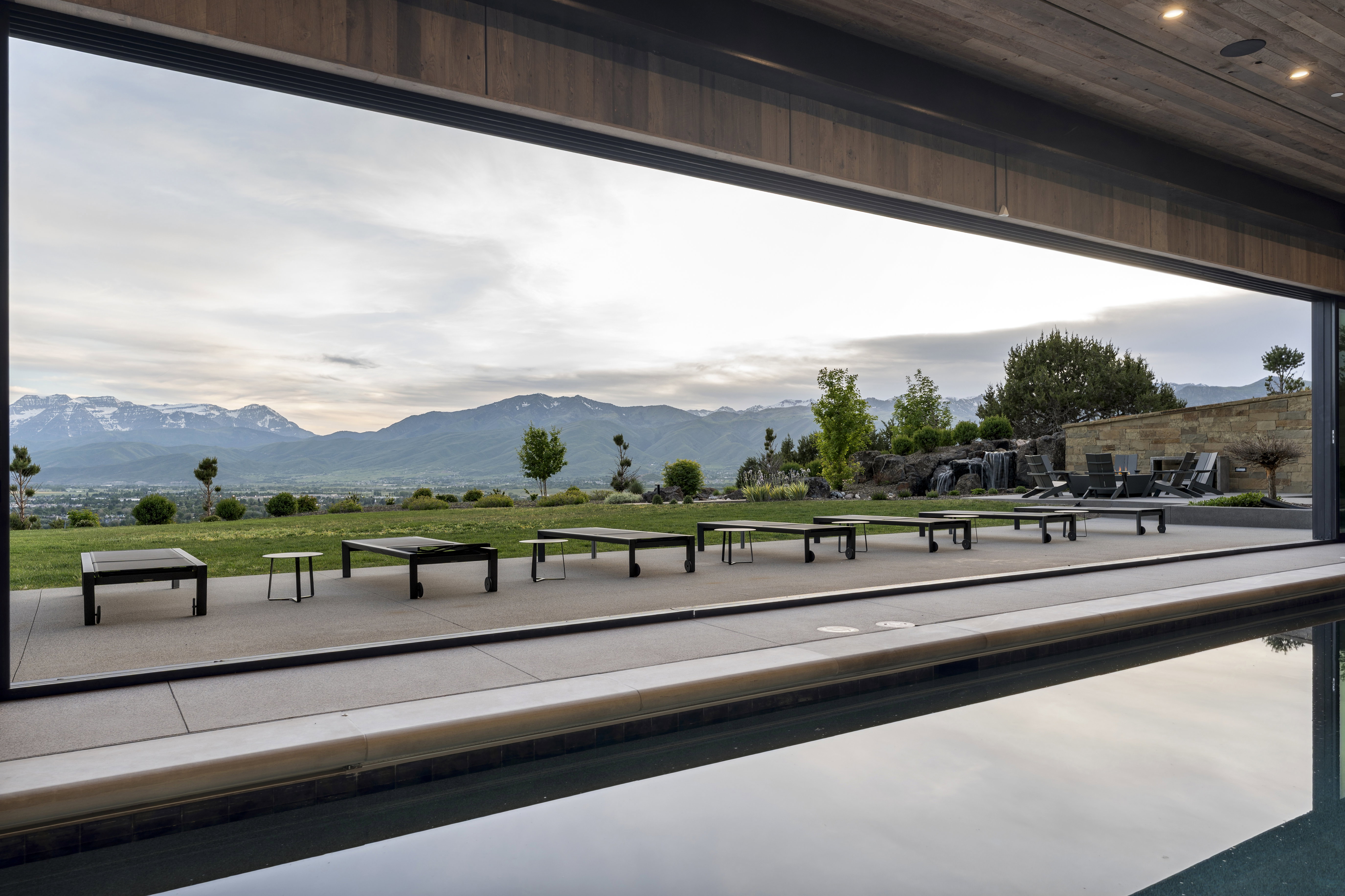 Expansive outdoor living area featuring a pool, a stone patio, and a water feature
