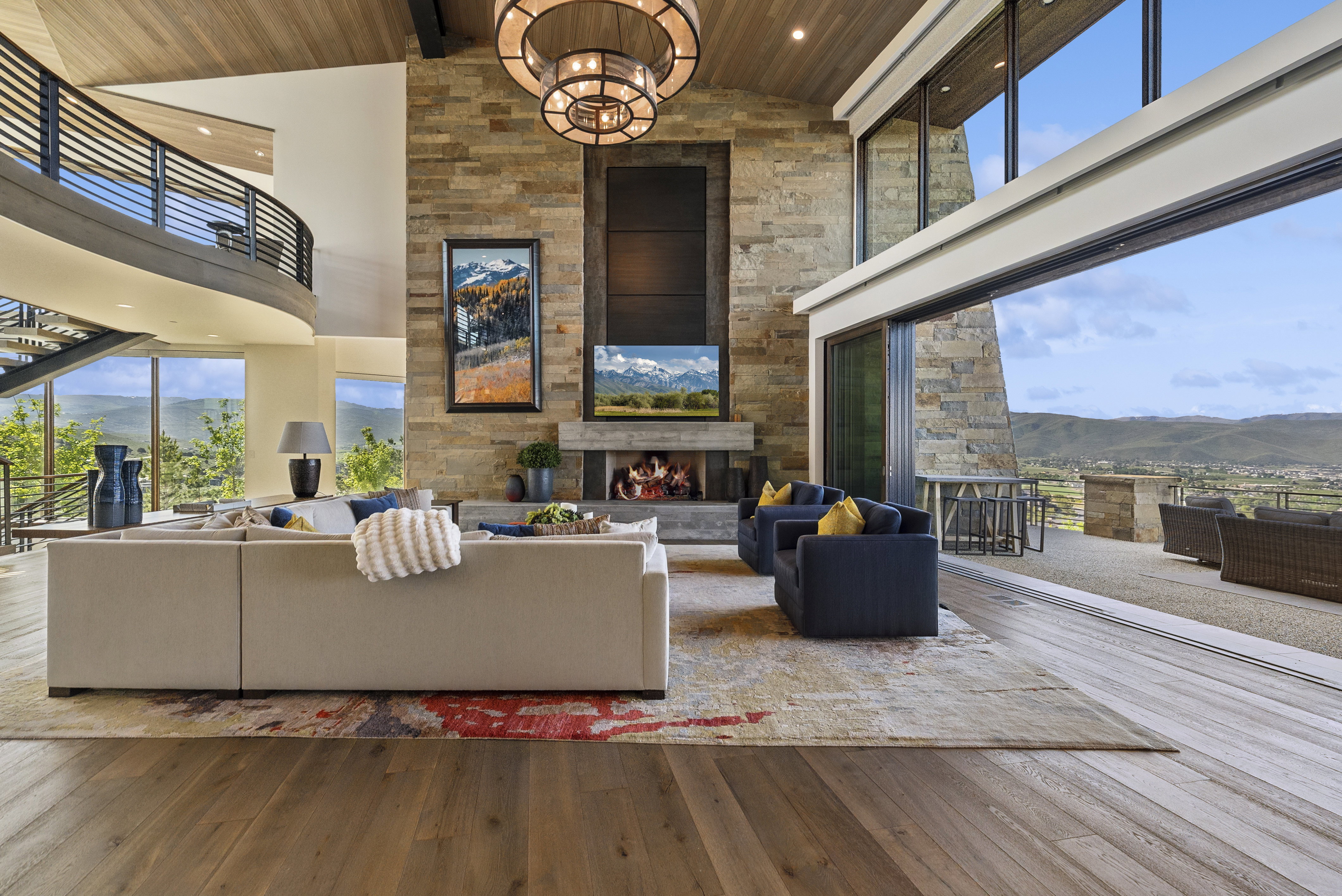 Great room featuring a floor-to-ceiling stone fireplace, high vaulted ceilings with wood-paneling, and large format wood-finish flooring