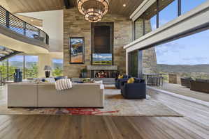 Great room featuring a floor-to-ceiling stone fireplace, high vaulted ceilings with wood-paneling, and large format wood-finish flooring