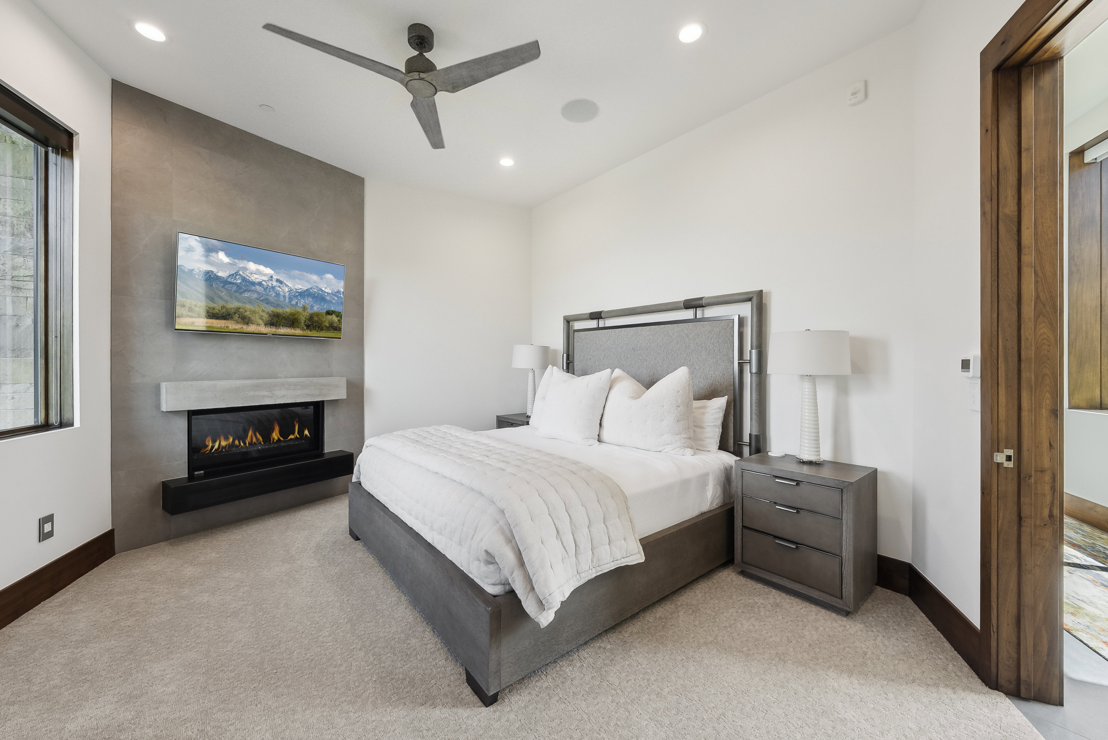 Bedroom featuring a textured accent wall with an integrated linear fireplace and mounted television