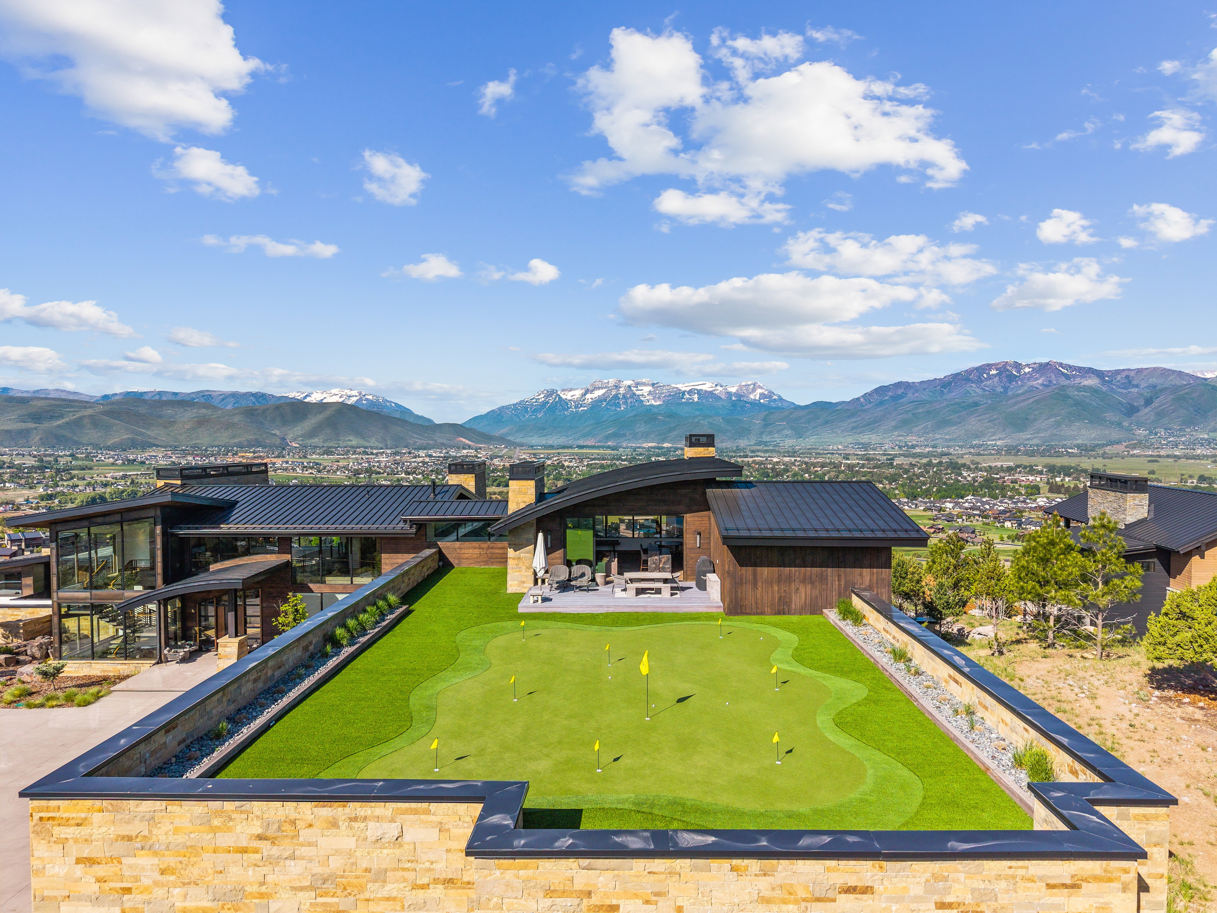Expansive putting green with multiple holes, bordered by a stone wall