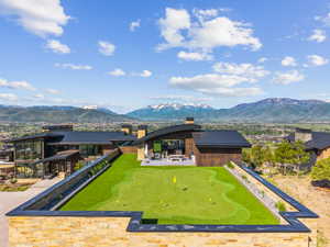 Expansive putting green with multiple holes, bordered by a stone wall